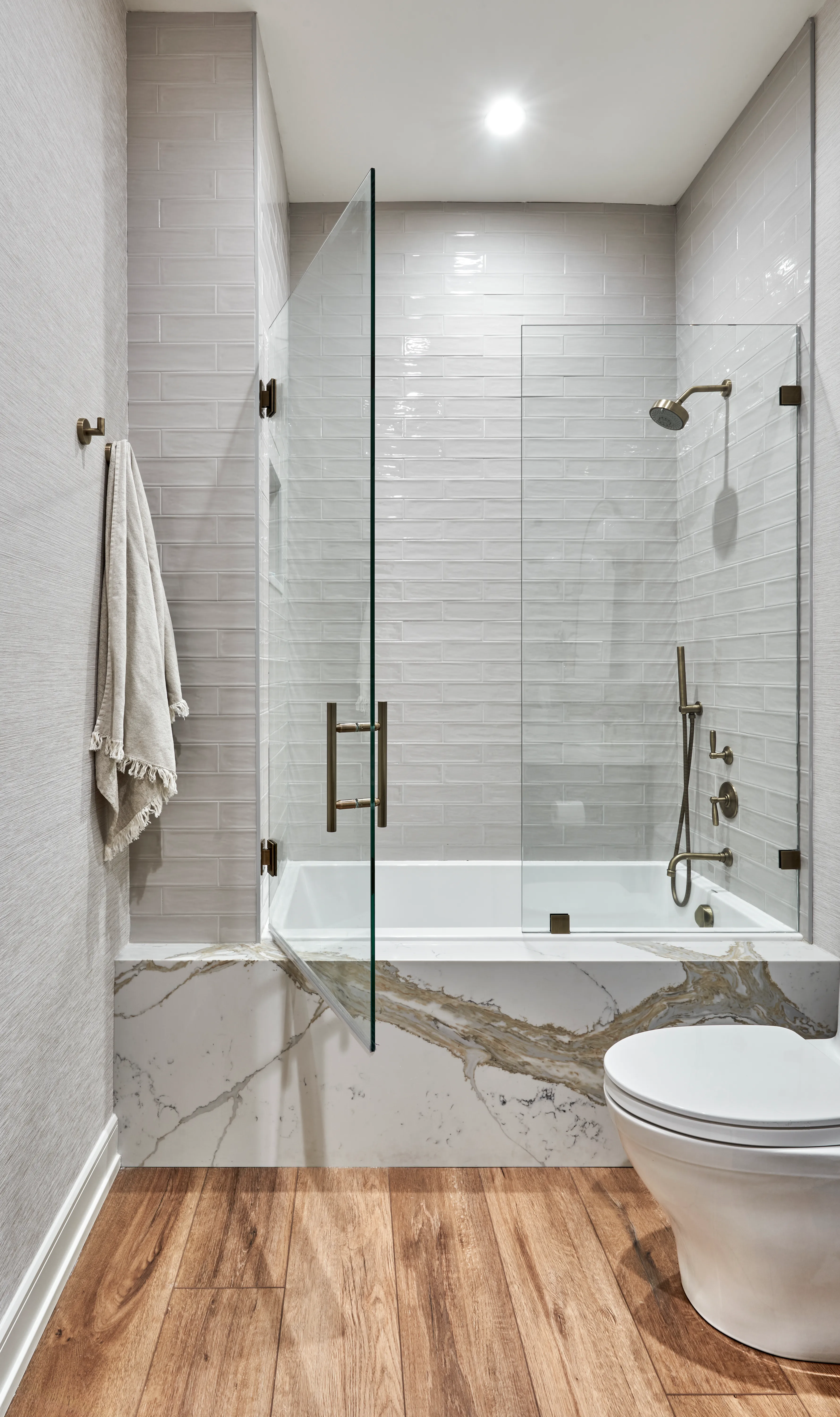 bathtub with a shower and sliding glass door