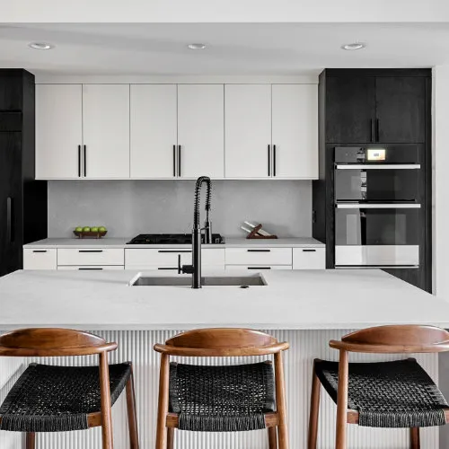 Modern kitchen with white cabinets, large island and black stainless steel fixtures