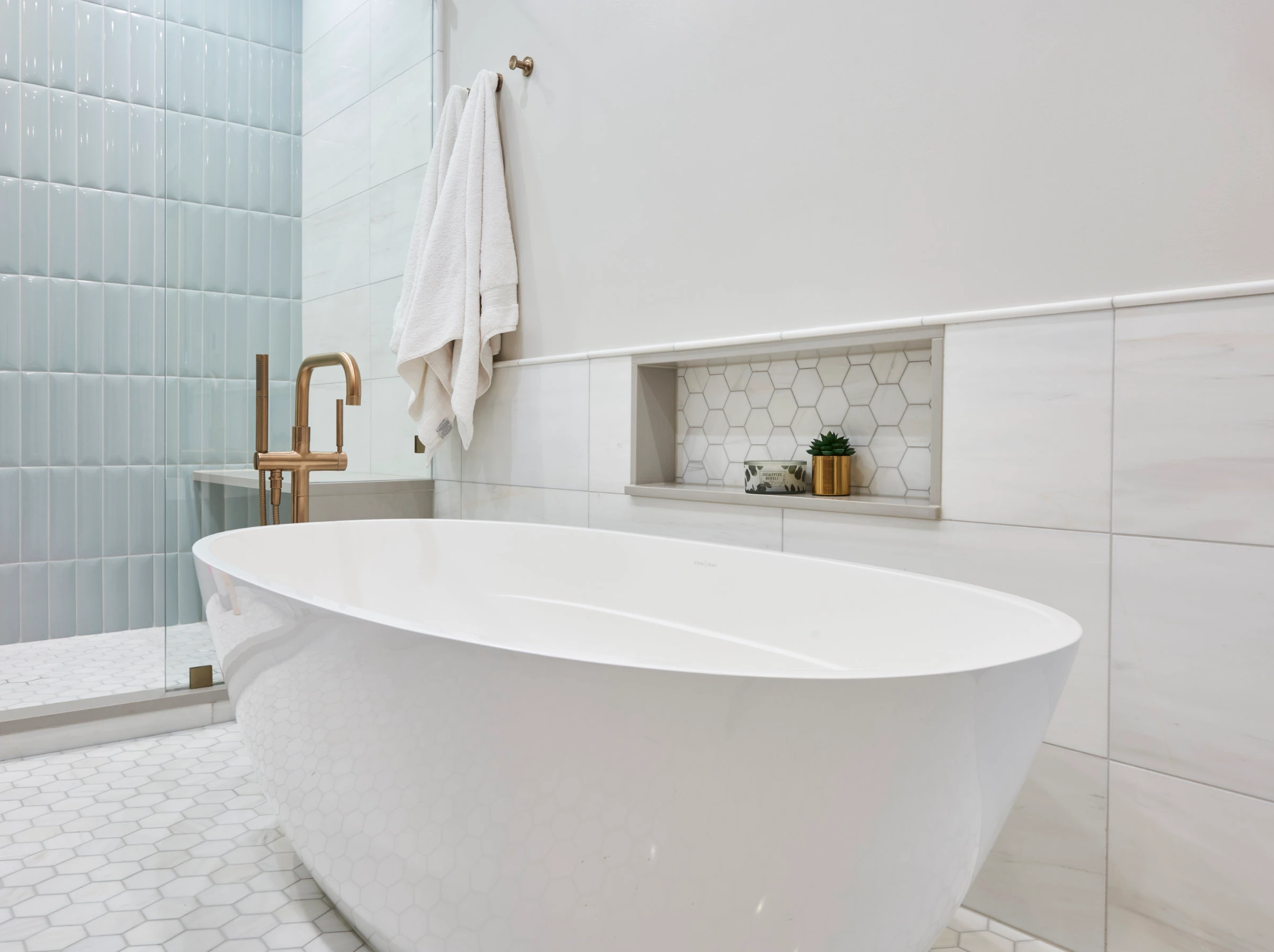 white freestanding tub with niche and bronze fixtures